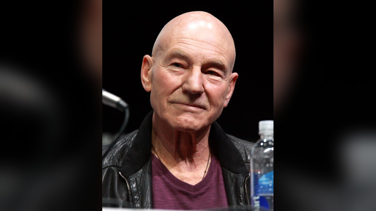 Patrick Stewart, sorridente, de casaco de cabedal preto e camisola bordô, num painel da Comic-Con de San Diego em 2013